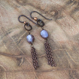 Mystic peach brown moonstone dangling earrings laid on a wood table, symbolizing inner glow and transformation.