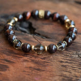 chakra balancing women's bracelet with garnet, tiger eye and smoky quartz on a wood table