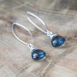 London Blue Crystal Earrings on wooden table, designed to promote calm, reduce anxiety and stress, and bring peace.