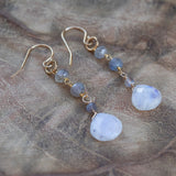 Moonstone and Labradorite earrings on wooden table, in light, crystal jewelry for emotional support and life change.