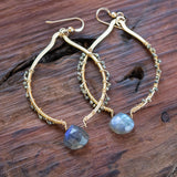 Beautifully laid on a wood table, pyrite, labradorite, and gold earrings for protection and life change.