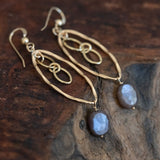 Soul Radiance: Mystic Peach Moonstone Marquise Style Gold Earrings beautifully laid on a wooden table.