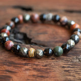 Unisex boho stretch healing spiritual bracelet for protection and vitality, featuring Red Creek Jasper, Pyrite, and Sugilite, laid beautifully.